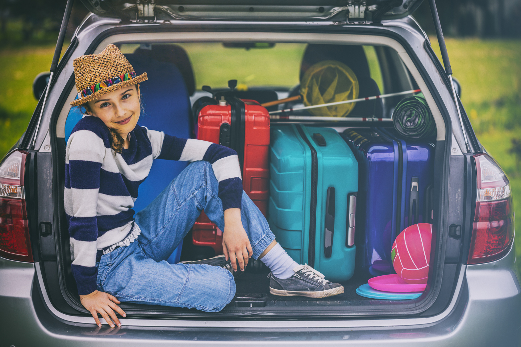 A hip girl in a car trunk looks happy.